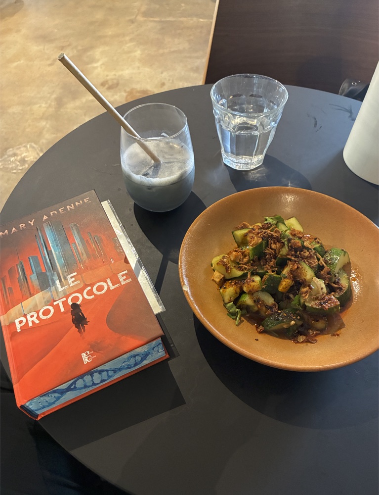 A table with Le Protocole book, a dish, and drinks